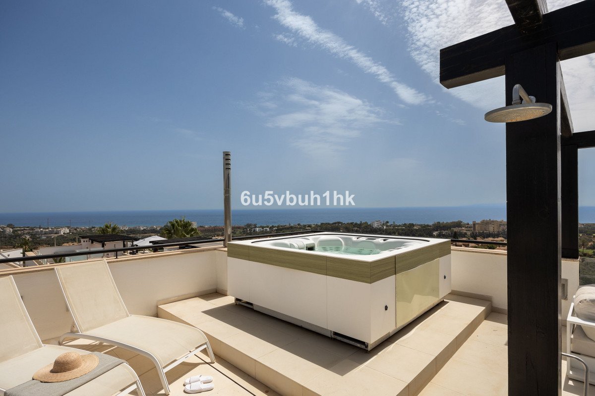 Modern terrace with a jacuzzi hot tub, lounge chairs, and a stunning sea view under a clear blue sky.