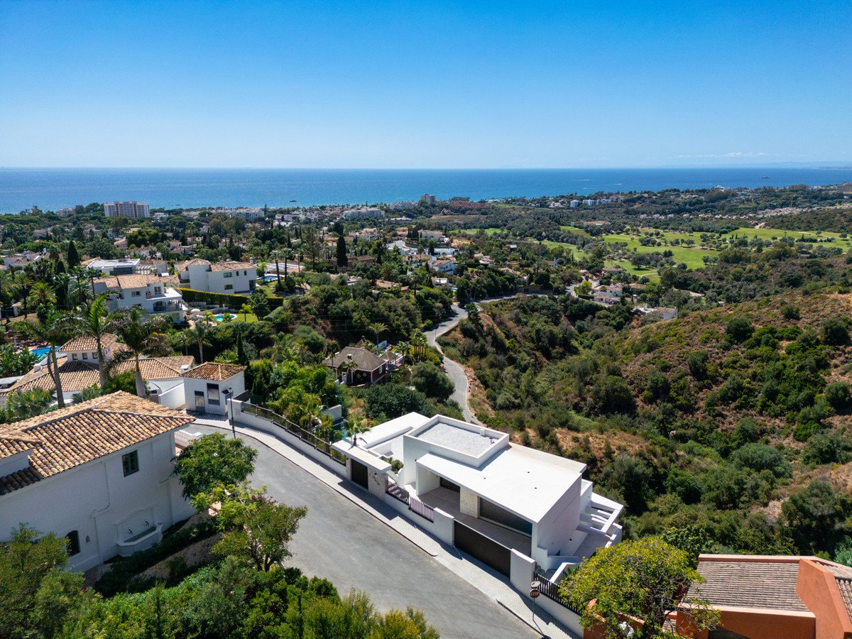 Modern villa with a stunning sea view, surrounded by lush greenery and overlooking a golf course.