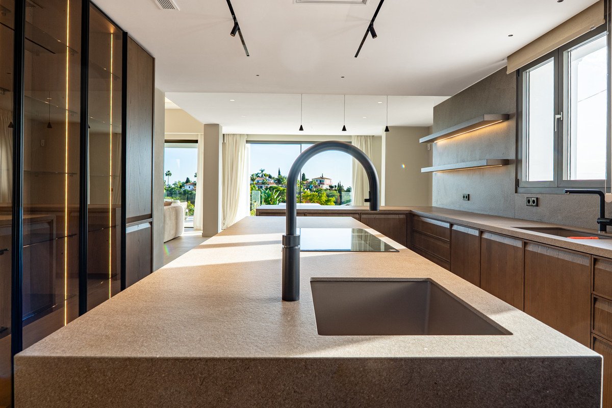 Modern kitchen with large island, sink, and panoramic outdoor view through large windows