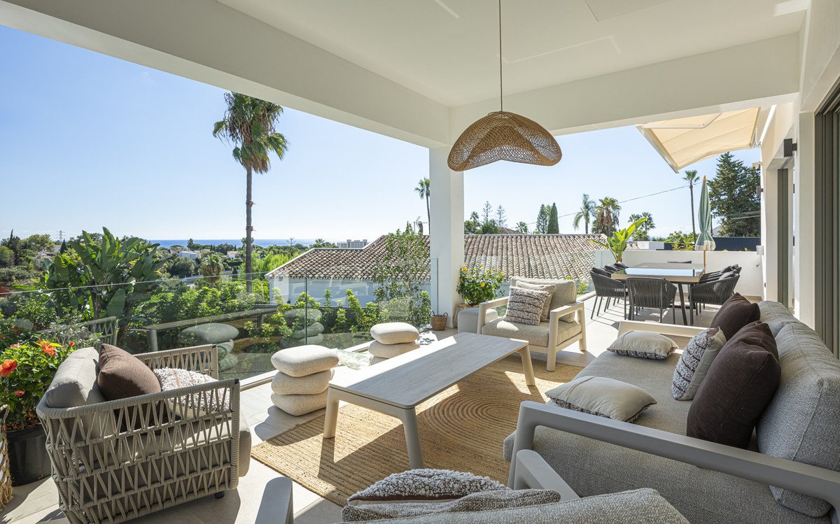 Modern outdoor living space with seating, dining area, and sea view