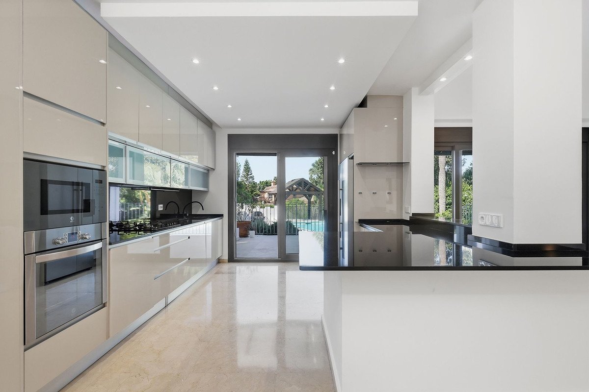 Modern open-plan kitchen with sleek cabinetry and a view of the swimming pool outside