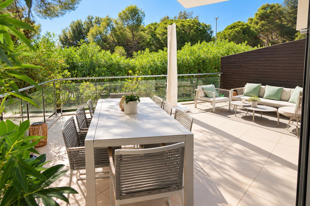 Spacious terrace with outdoor dining table, lounge seating, and lush greenery providing a serene view.