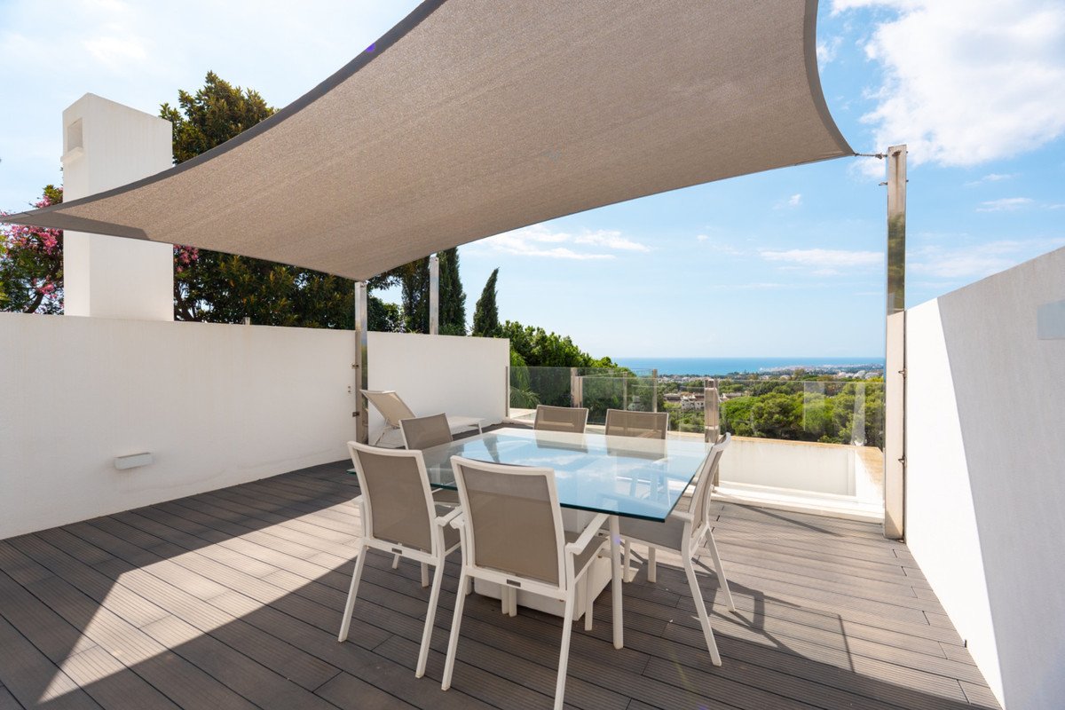 Outdoor dining terrace with sea view and shade sail