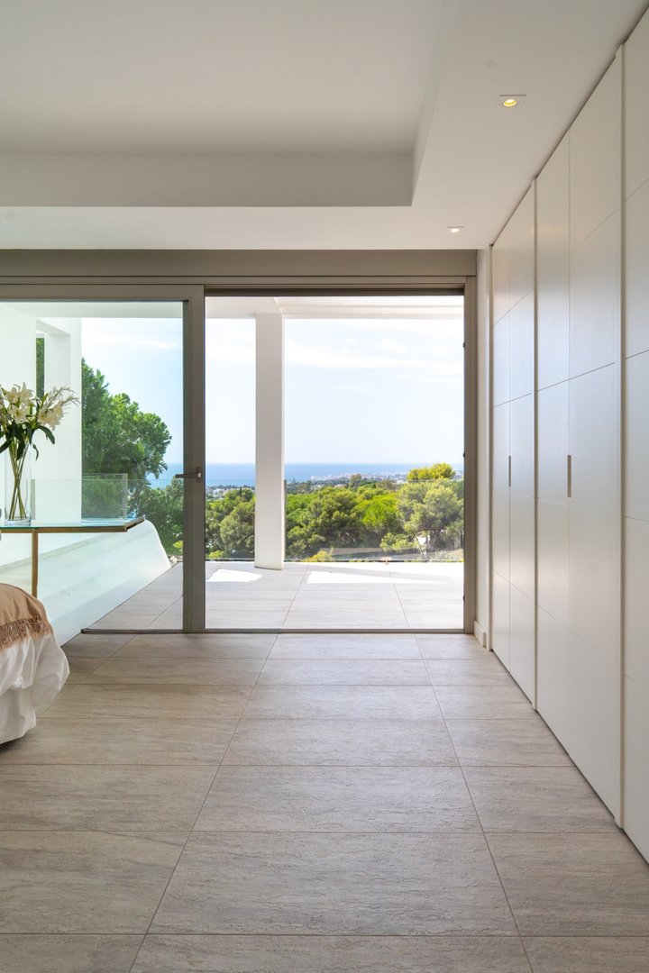 Modern bedroom with large sliding doors opening to sea view and outdoor terrace