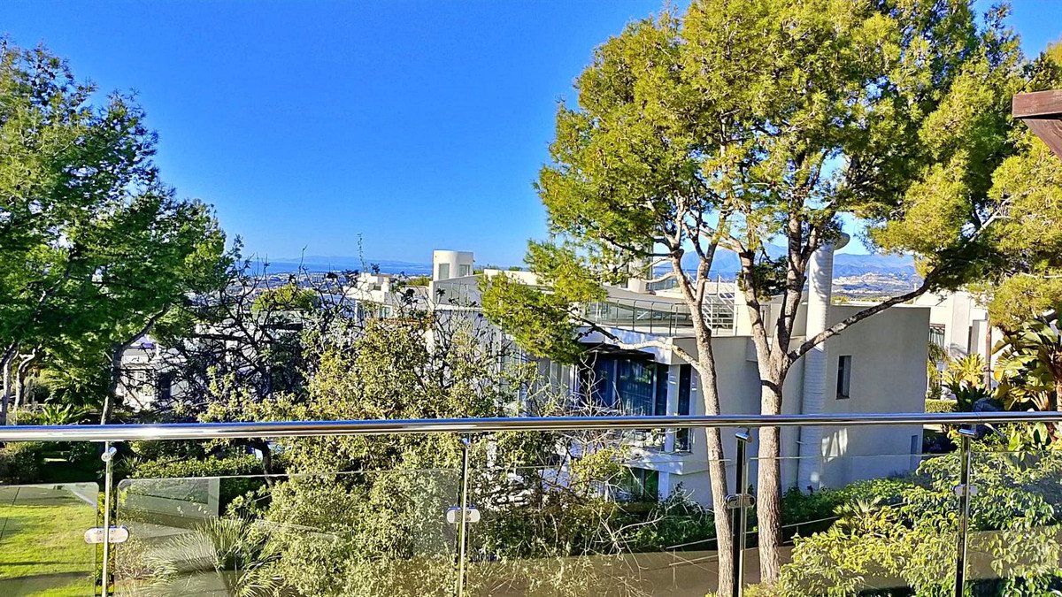Balcony with glass railing, ocean view, and surrounding trees
