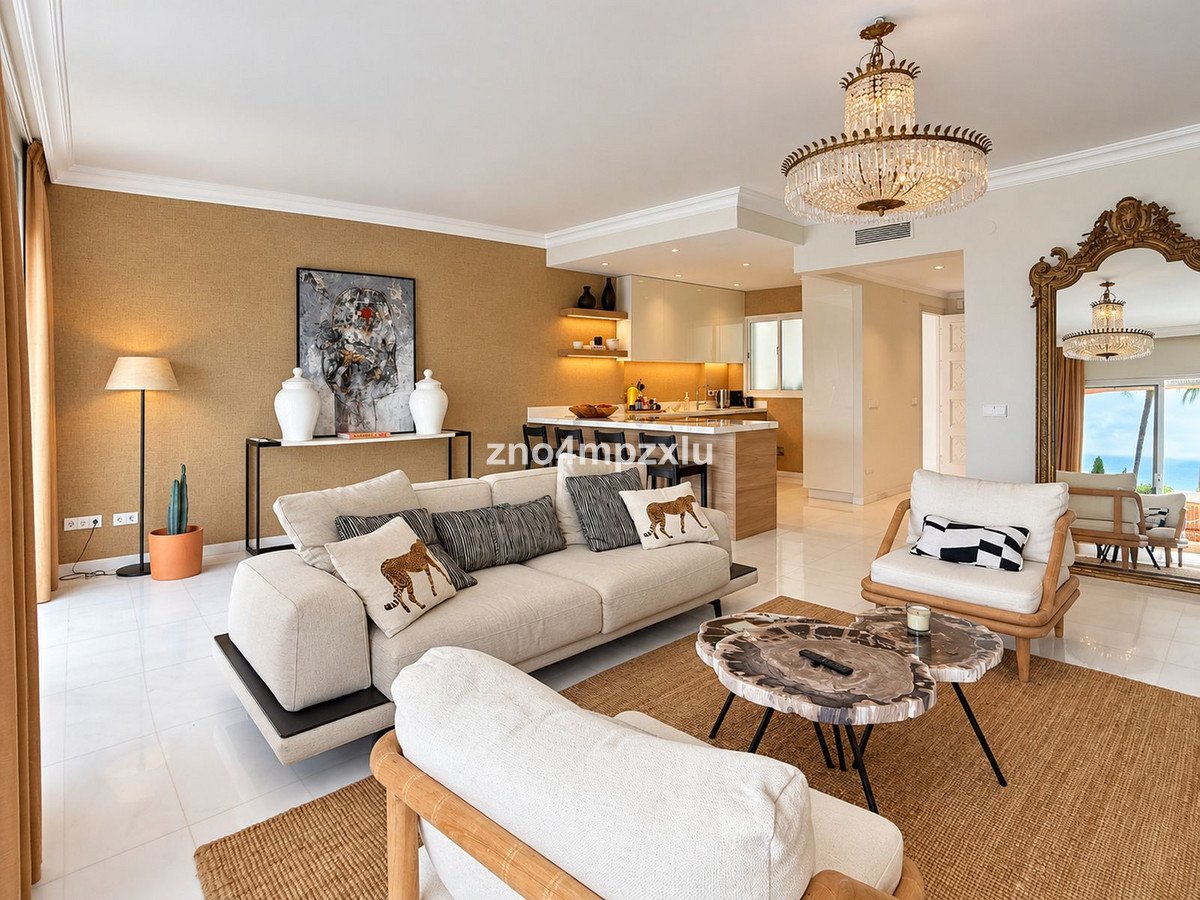 Elegant living room with a sea view, featuring a plush sofa, comfortable armchairs, and a stunning crystal chandelier.
