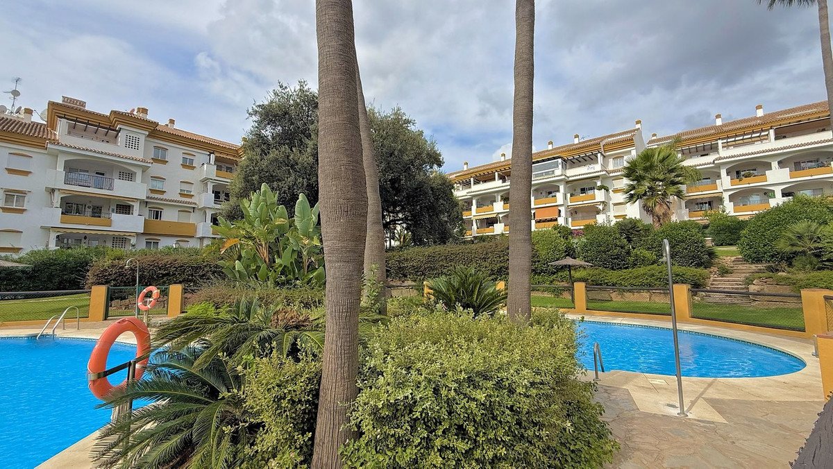Outdoor pool area with palm trees and apartment buildings in resort