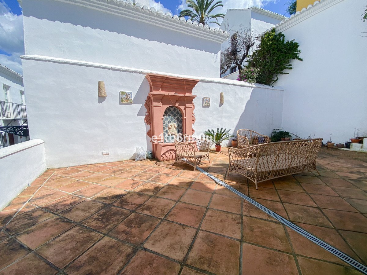 Terrace with terracotta tiles, wicker furniture, and a decorative fountain, offering a charming outdoor living space.