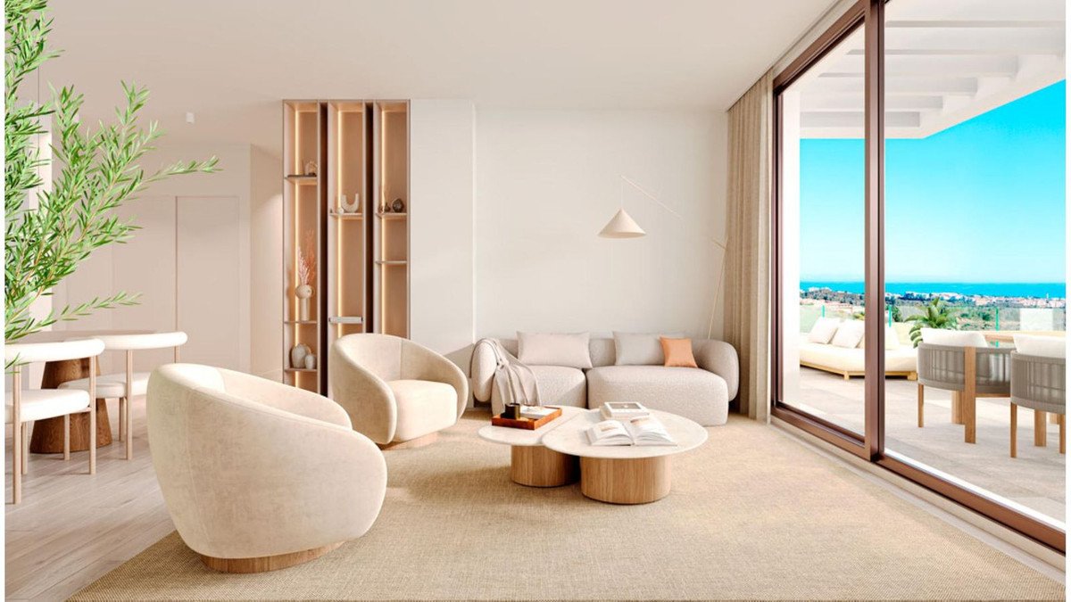 Modern living room with plush seating and coffee tables, leading to a balcony with an ocean view.