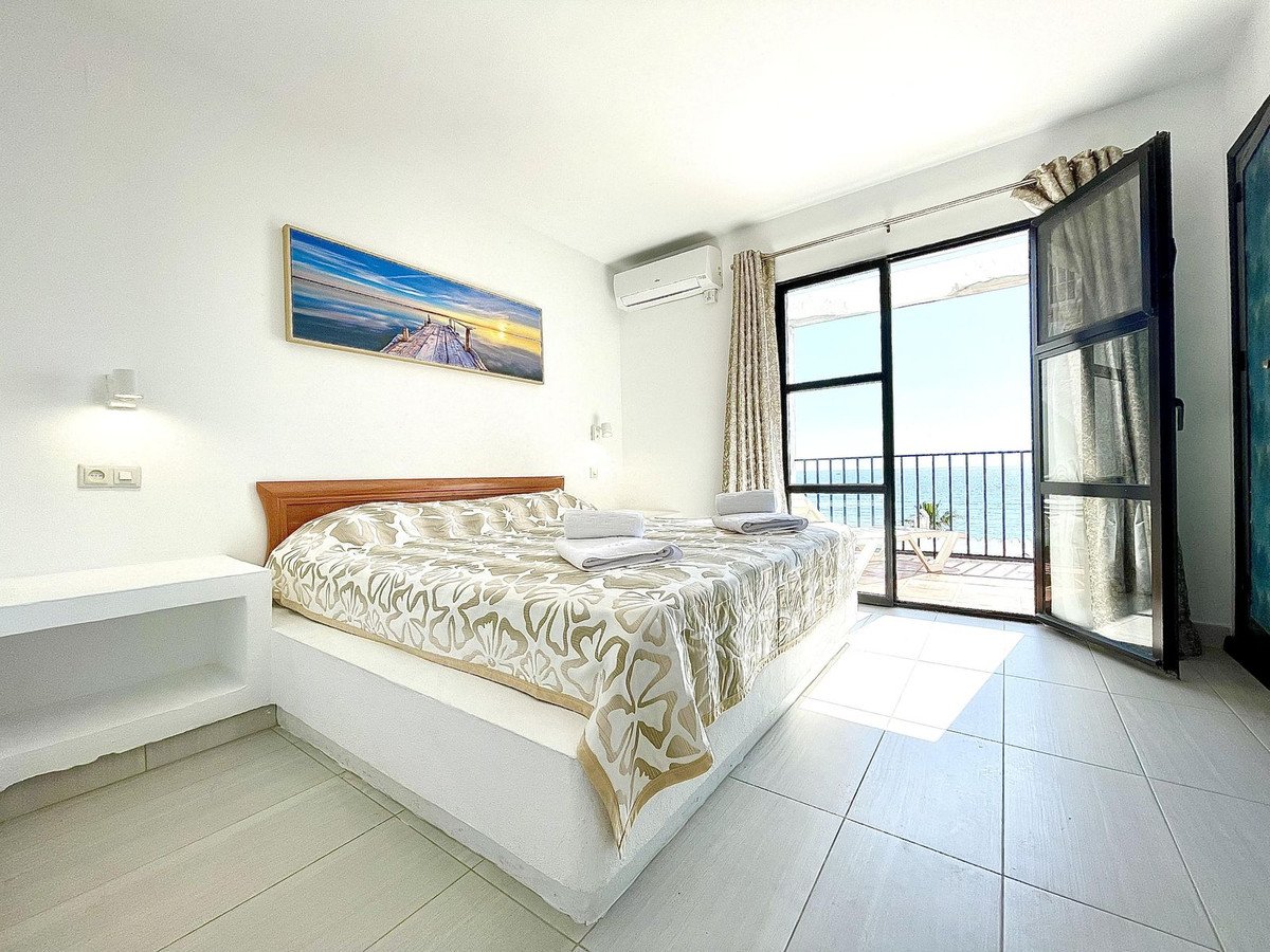 Bedroom with a king-size bed, air conditioning, and a balcony with a stunning sea view.