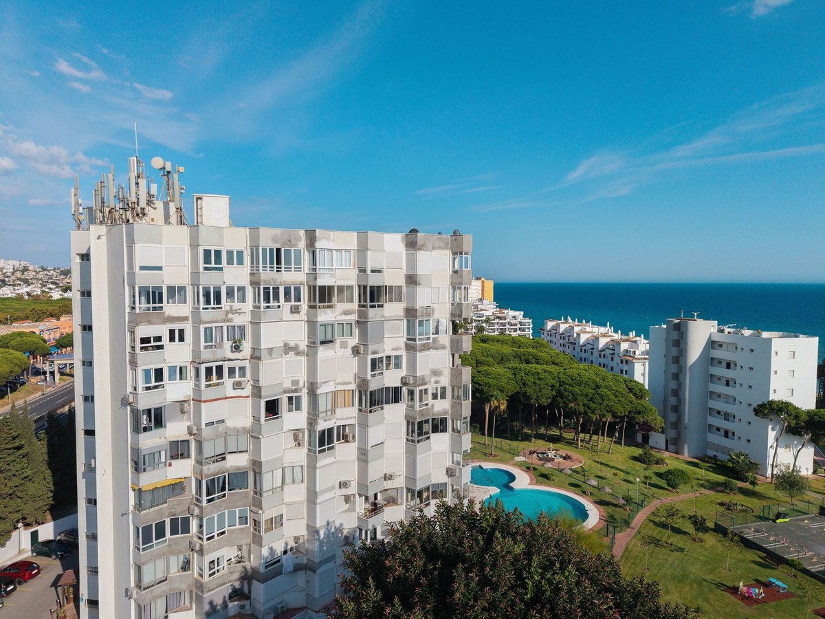 Aerial view of an apartment building with sea view and swimming pool.