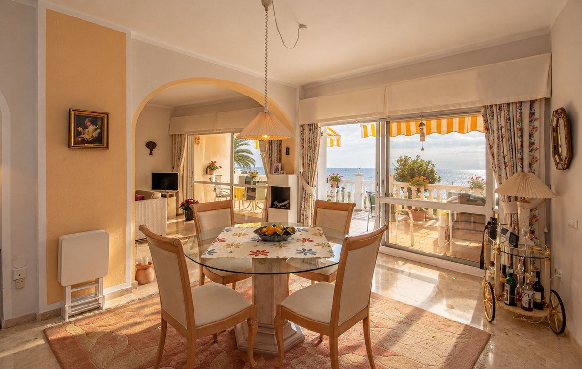 Dining room with a glass table and chairs, featuring a stunning sea view from the balcony.