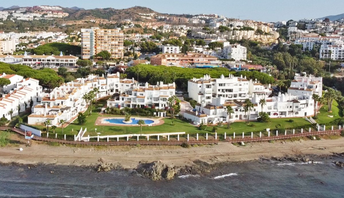 Apartment complex with sea views, communal pool, and lush green gardens, overlooking the ocean.