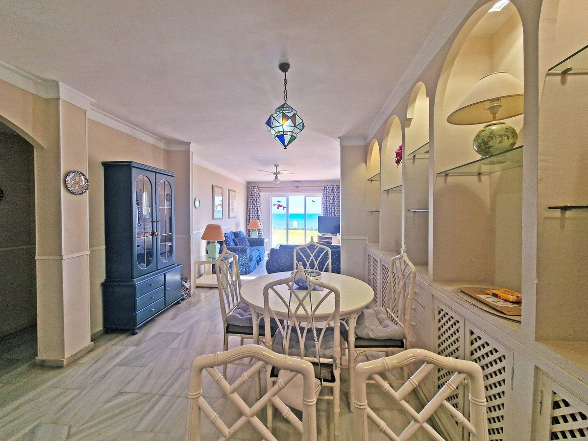 Dining area and living room with a beautiful sea view through the balcony doors and white furniture.