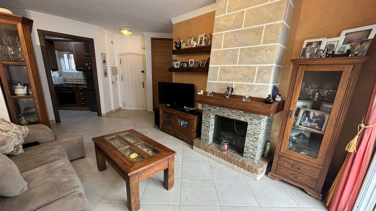 Living room with stone fireplace, wooden furniture, and tiled flooring.