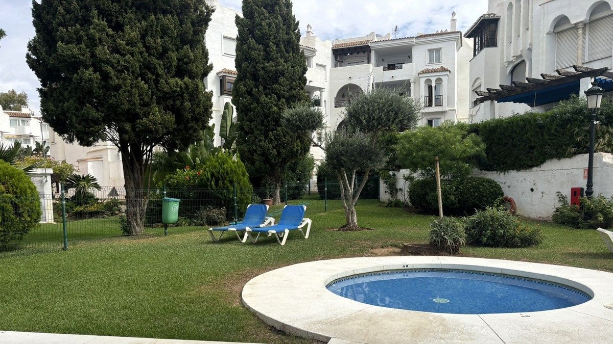 Apartment garden with jacuzzi, lawn chairs, and white buildings in background