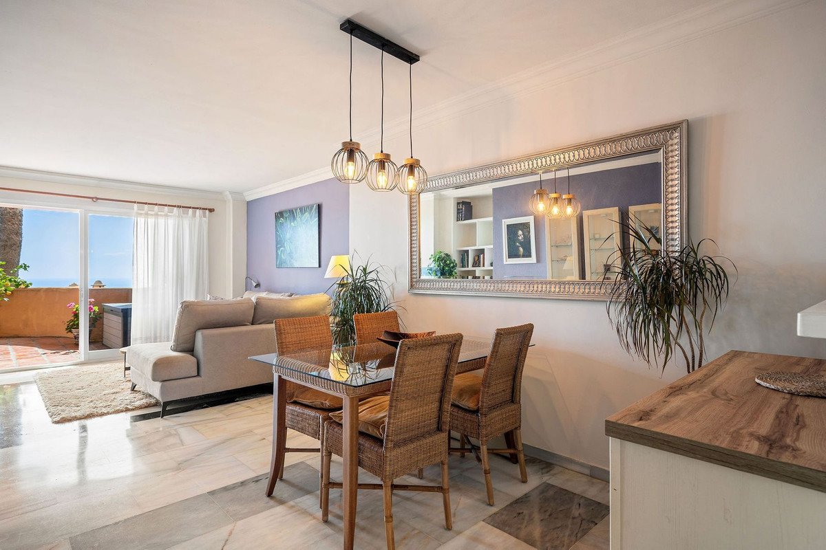 Open-plan living and dining area with ocean view, modern decor, and sliding glass doors