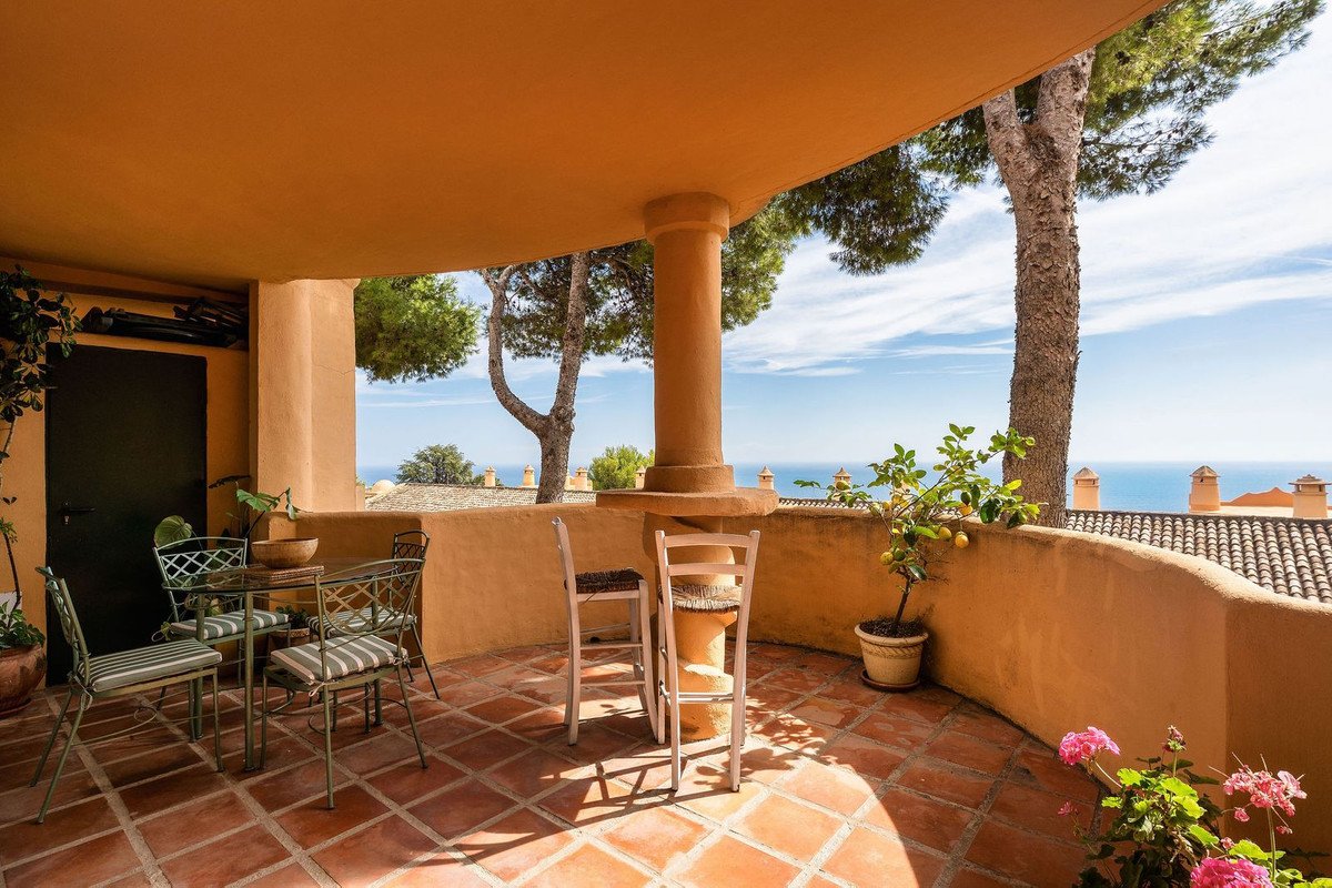 Outdoor terrace with dining set overlooking sea and trees