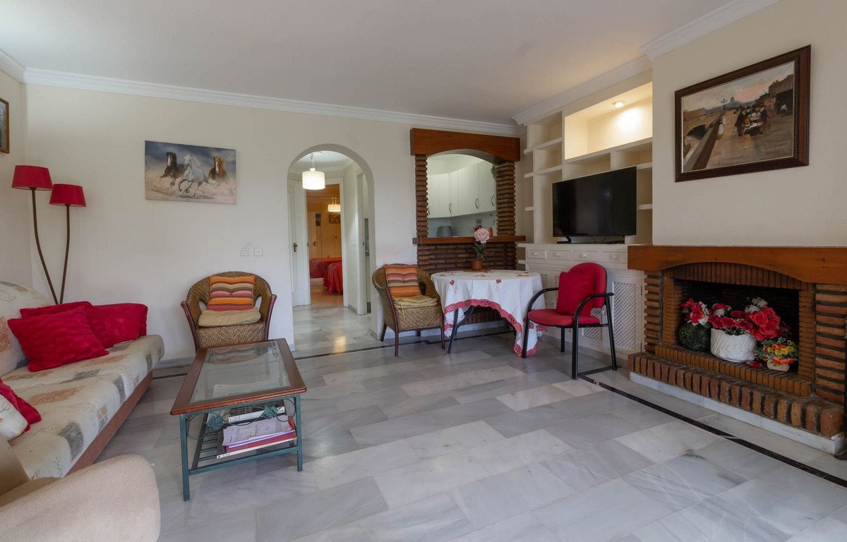 A living room with a fireplace, TV, sofa, armchair, and a small table with chairs.