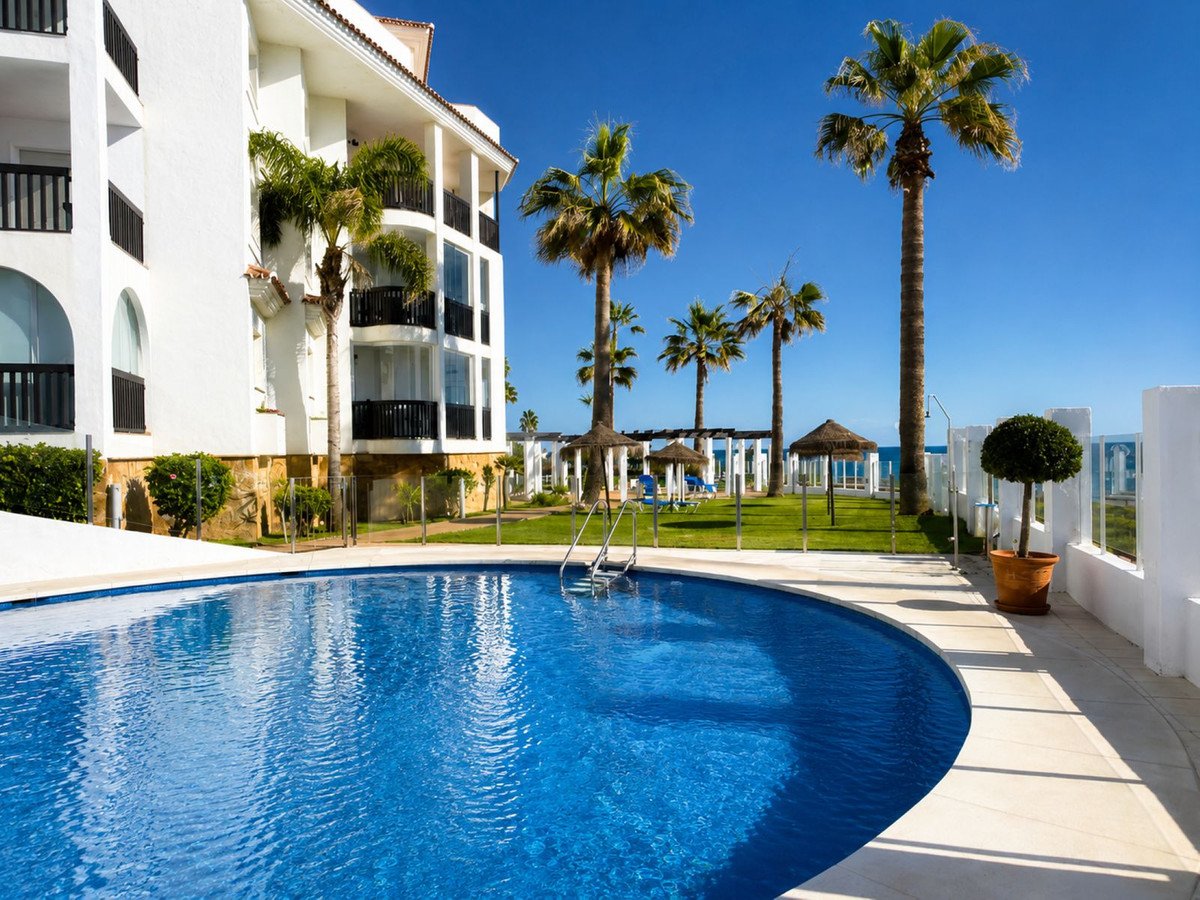 Swimming pool with palm trees near white apartment building