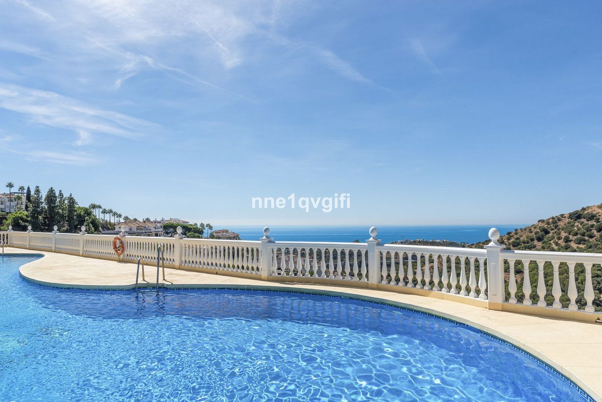 A luxurious swimming pool with a white balustrade overlooking the Mediterranean Sea under a clear blue sky.