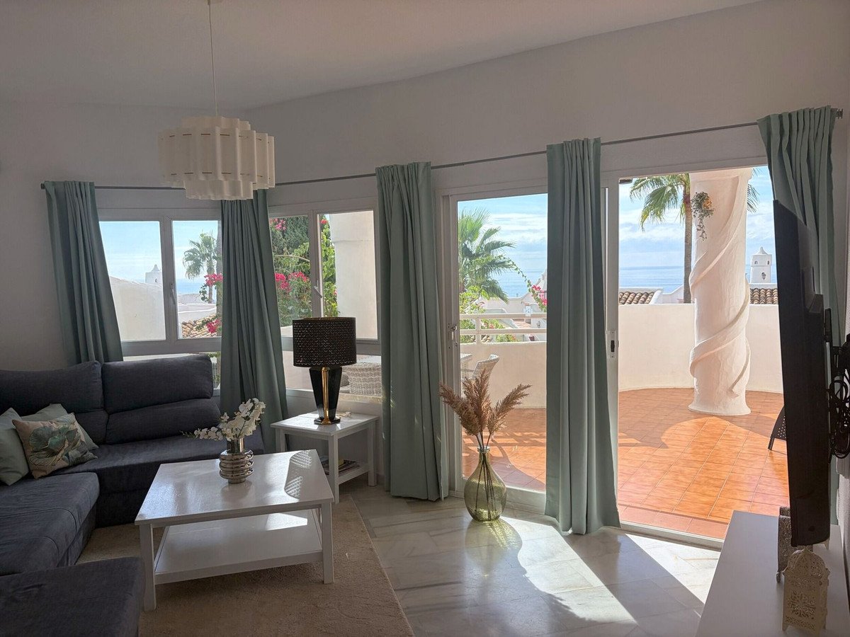 Bright living room with sea view, sofa, coffee table, and balcony access