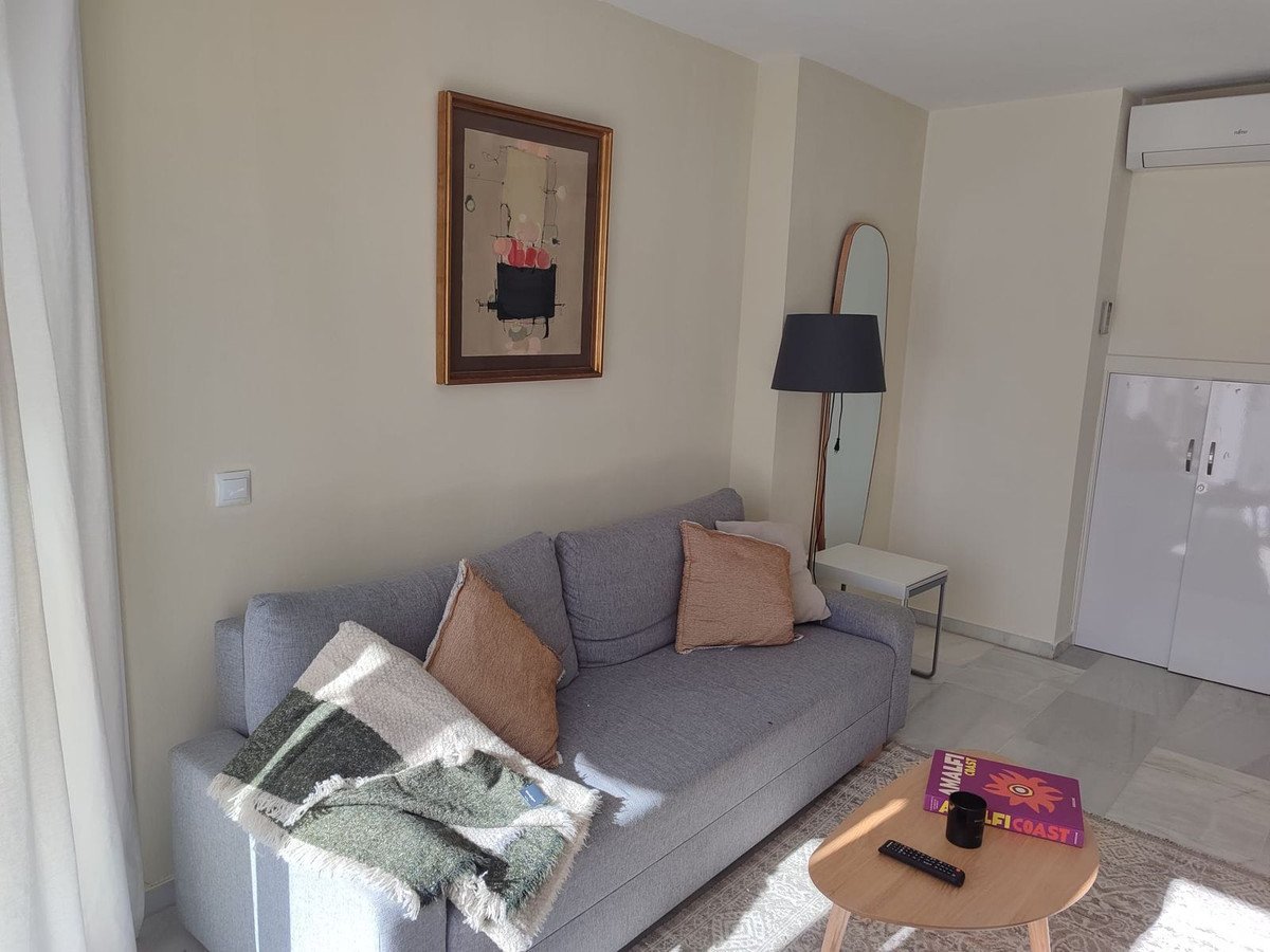 Modern living room with a grey sofa, decorative pillows, a throw blanket, and artwork on the wall.