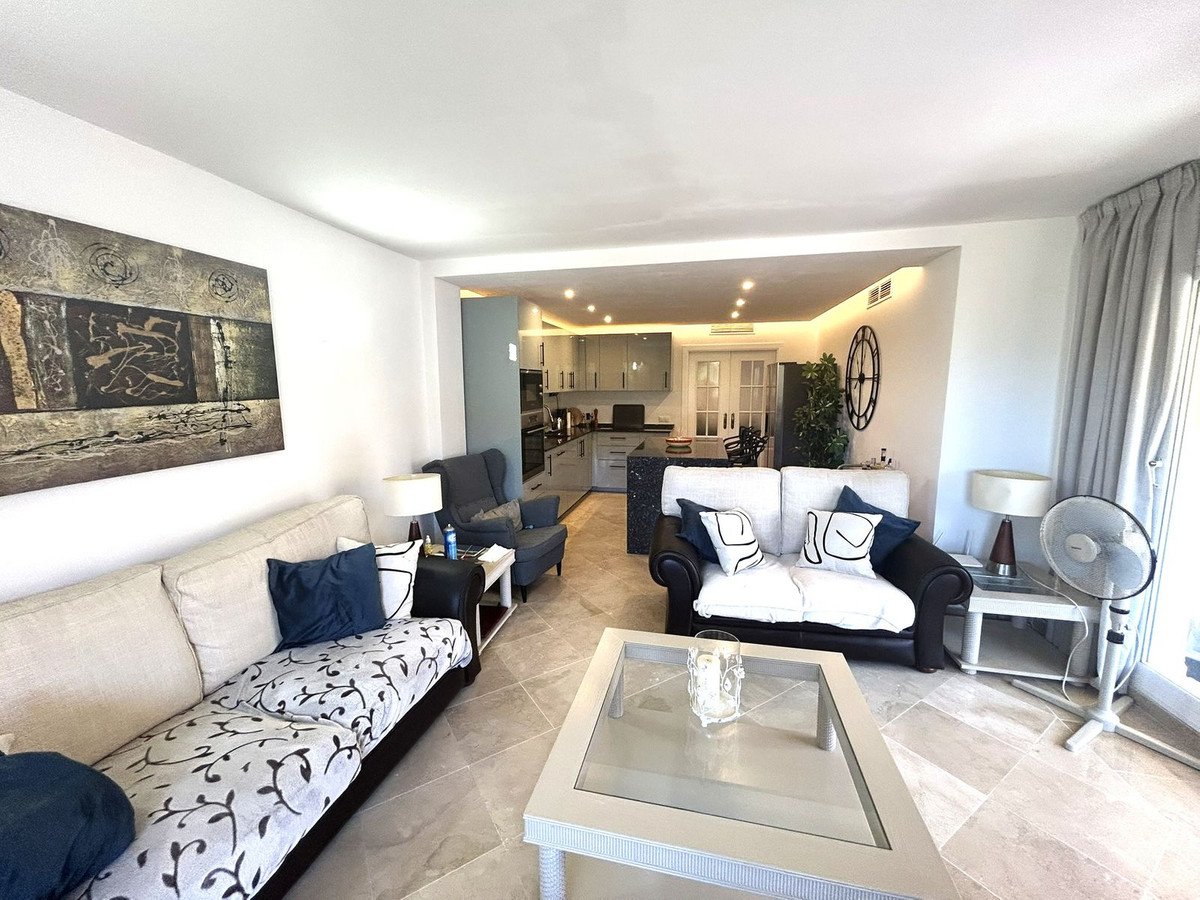 Modern living room with open-plan kitchen, comfortable sofas, and stylish decor. Features a large abstract painting.