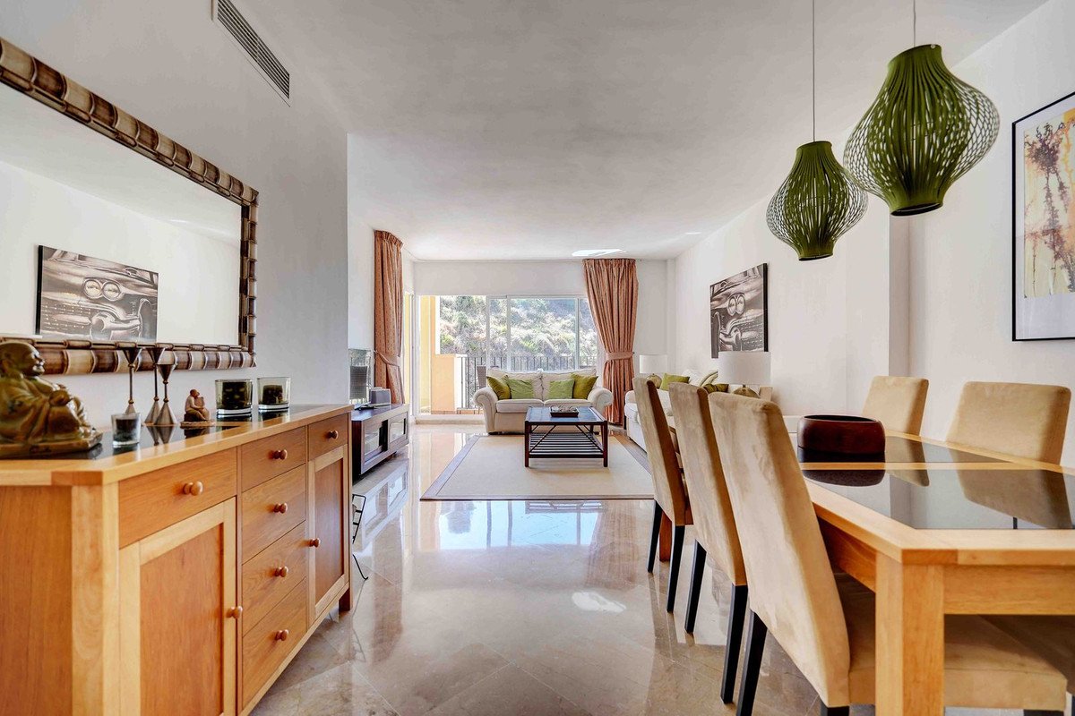 A well-lit living and dining area with a view of trees through a large sliding glass door.