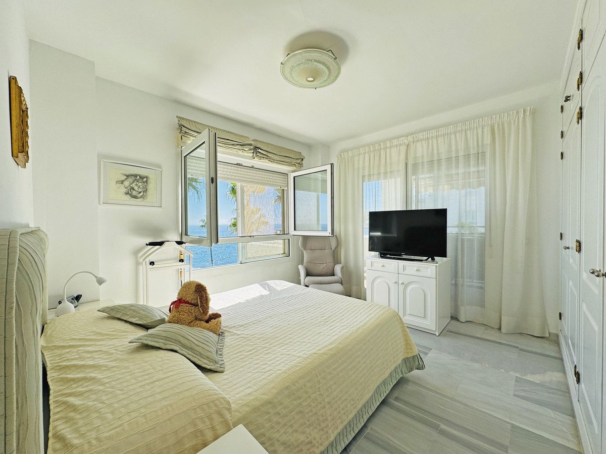 Bright master bedroom with sea view, large bed, and white furniture