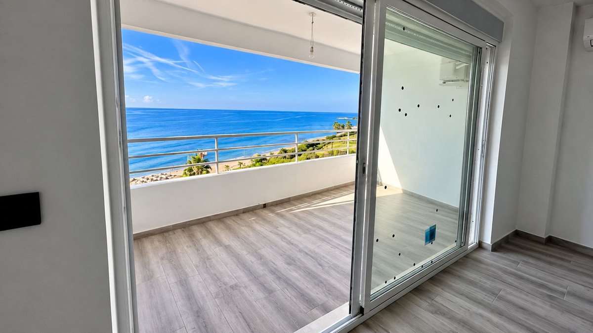 Interior view of a modern apartment balcony with a panoramic sea view and a sandy beach.