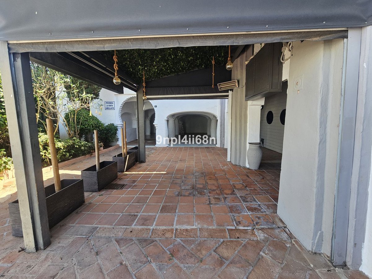 Covered patio with tiled floor, archway view, and outdoor planters