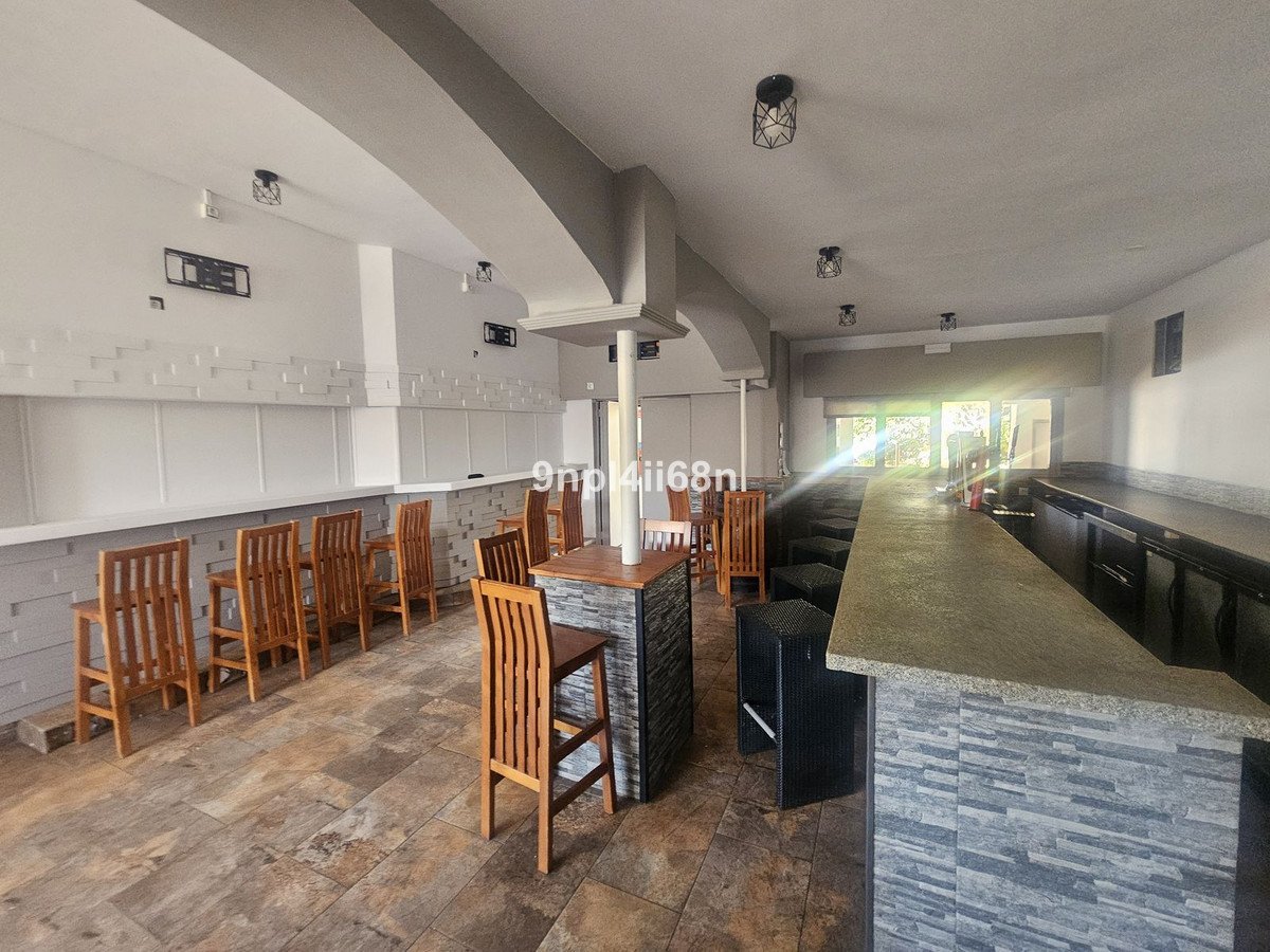Bar lounge with wooden stools, stone counter, and tiled flooring