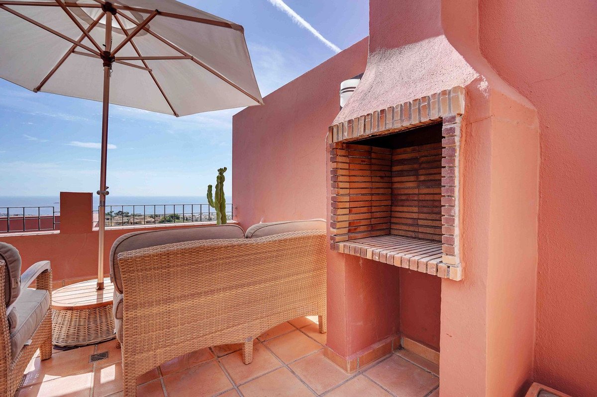 Terrace with BBQ, wicker sofa, umbrella, and sea view.