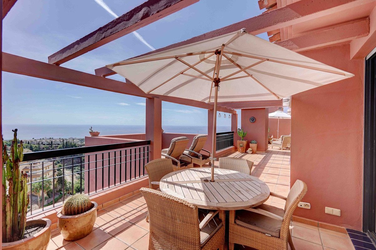 Spacious terrace with dining set, lounge chairs, and a beautiful sea view under a large umbrella.