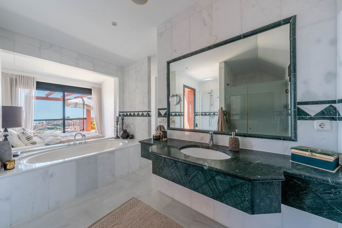 Luxurious master bathroom with large bathtub, green marble vanity, and a stunning view of the sea from the window.