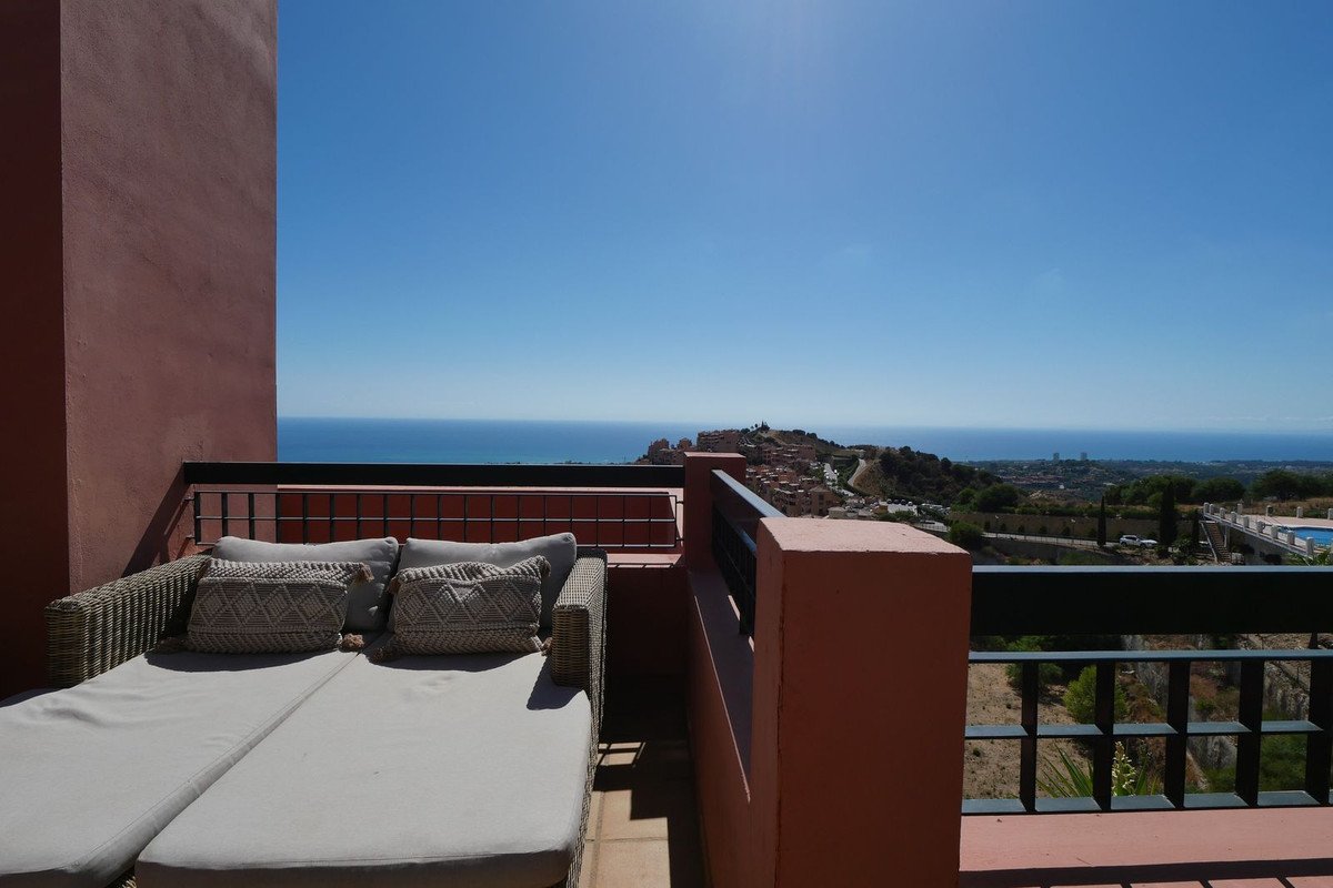 Spacious terrace with a daybed and pillows, offering panoramic sea and town views under a clear blue sky.