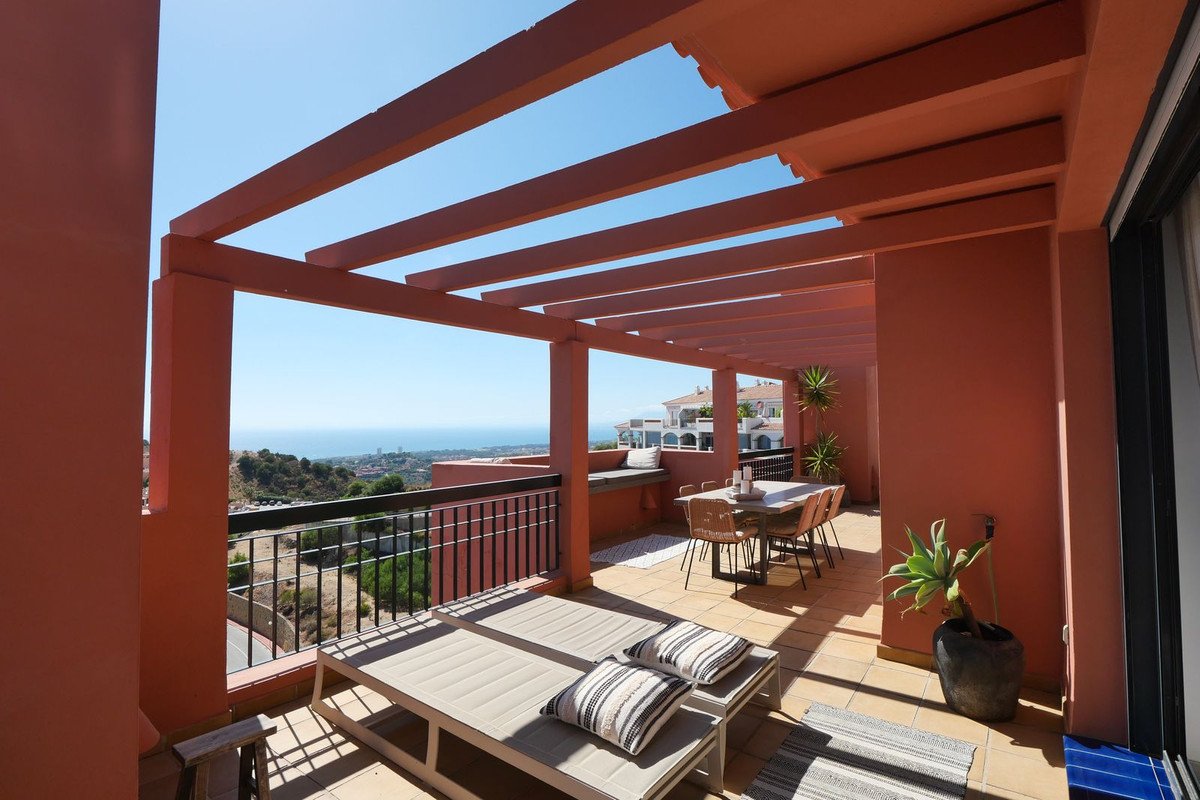 Terrace with sea view, dining table and chairs, and sun loungers under a pergola.