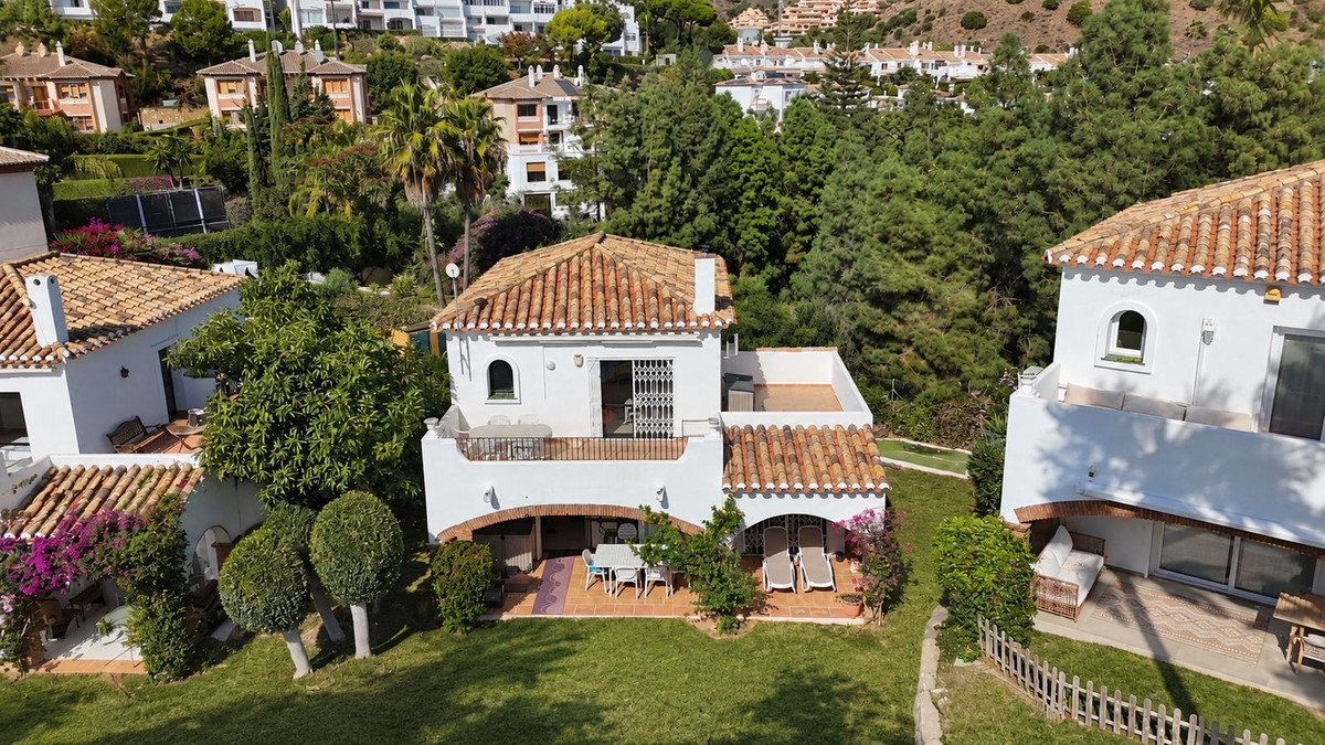 Aerial view of a white villa with terracotta roof, outdoor seating, and surrounding greenery