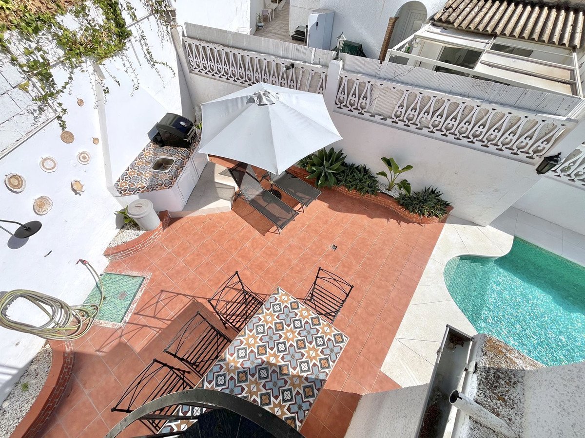Outdoor terrace with a pool, dining table, chairs, and an outdoor kitchen with a barbecue area.
