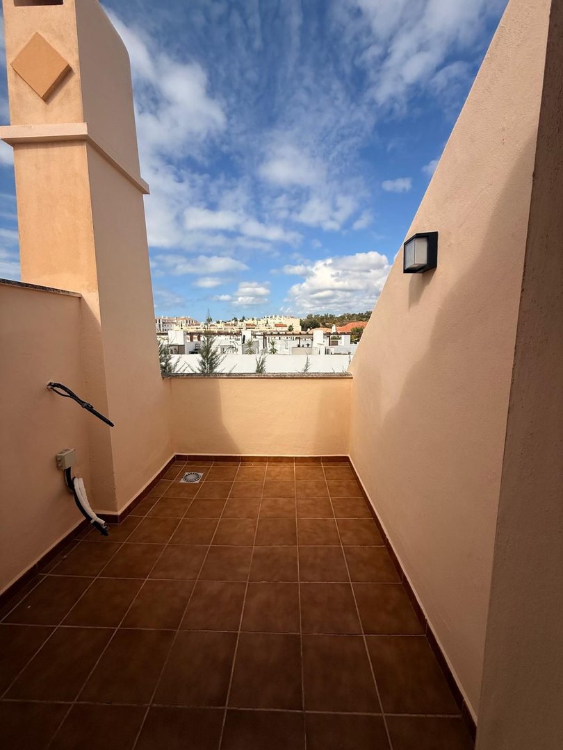 Terrace with tiled floor and a view of rooftops under a blue sky with clouds. Features a chimney and outdoor light.