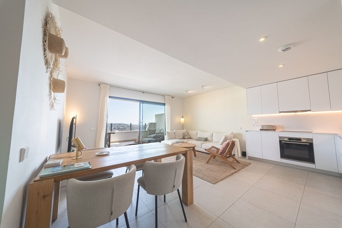 Modern open-plan living room with dining area, sofa, kitchen, and sea view through large windows