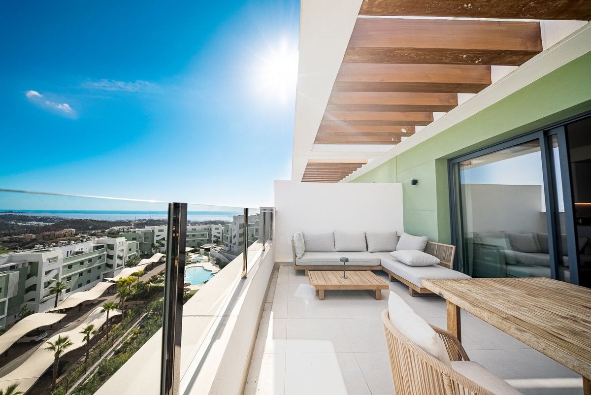 A balcony with outdoor furniture overlooking a sea view and nearby buildings