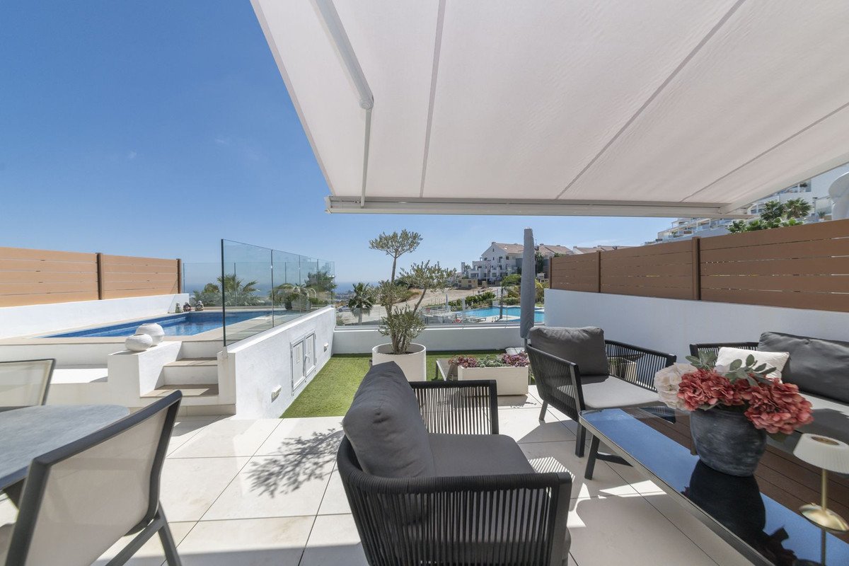 A modern terrace with a small pool, comfortable seating, and a beautiful sea view under a retractable awning.
