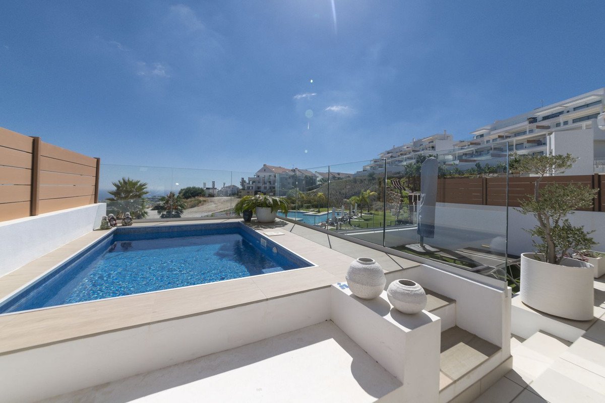 A private swimming pool and terrace with a view of the sea and modern apartment buildings.
