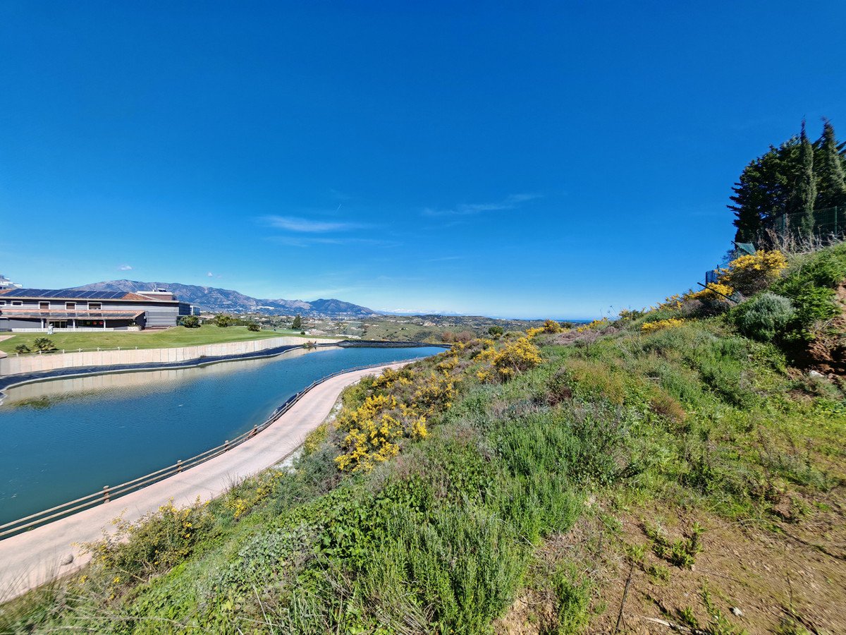 Villa with panoramic views of a lake, green hills, and distant mountains under a clear blue sky.