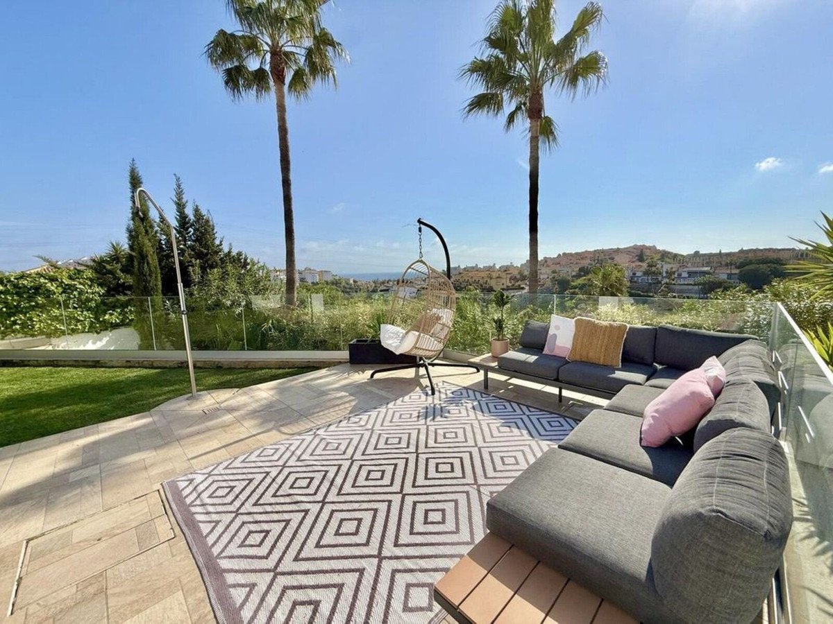 Outdoor patio with seating, palm trees, and sea view