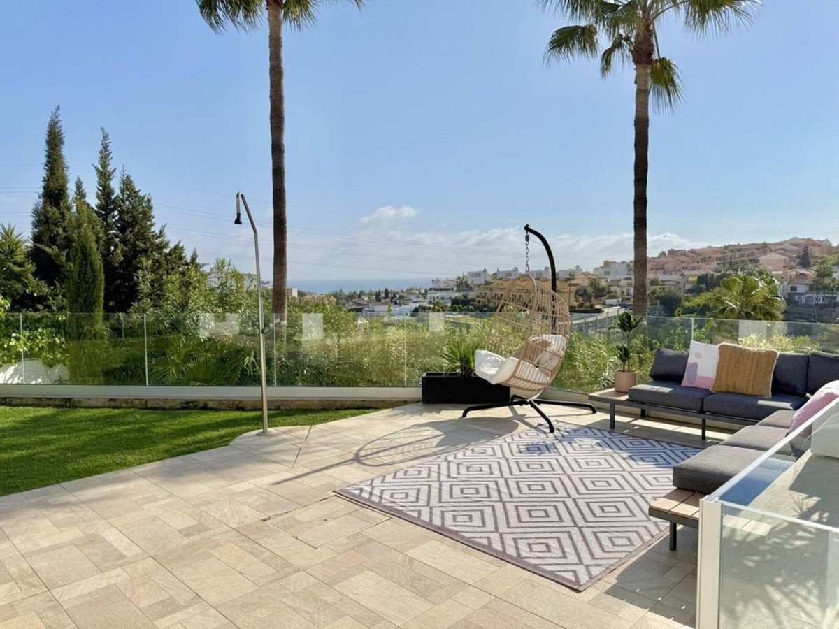 Outdoor patio with sea view, palm trees, and modern seating