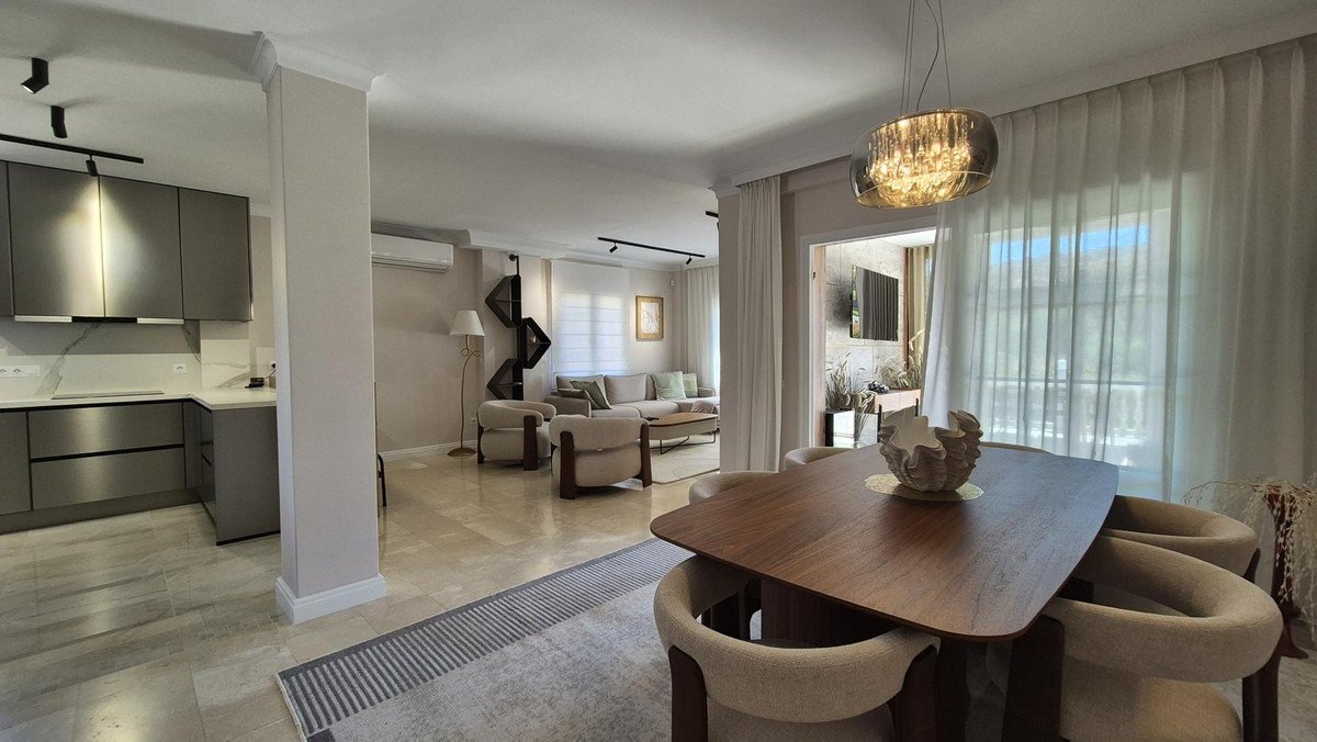 Modern open-plan living, dining, and kitchen area with a dining table and comfortable seating, featuring a well-lit interior.