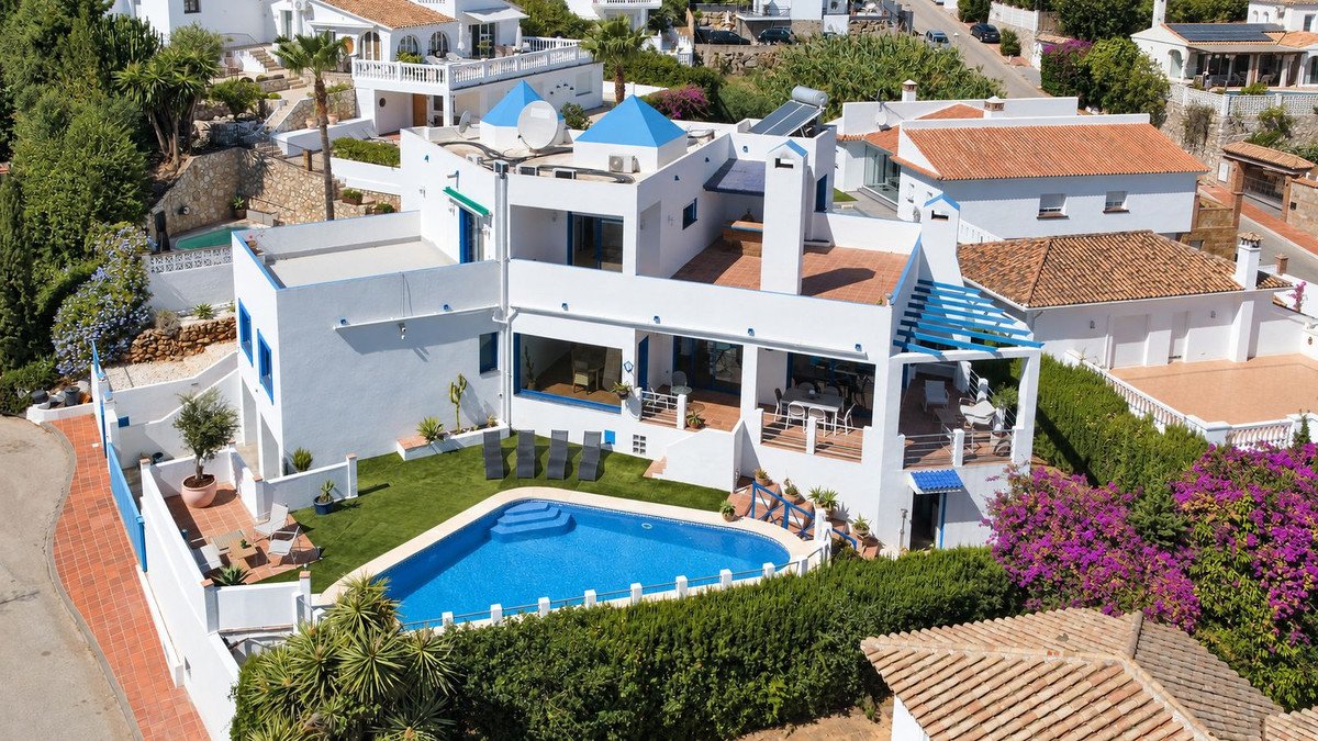Modern white villa with blue accents, featuring a private swimming pool, garden, and terrace with a sea view.